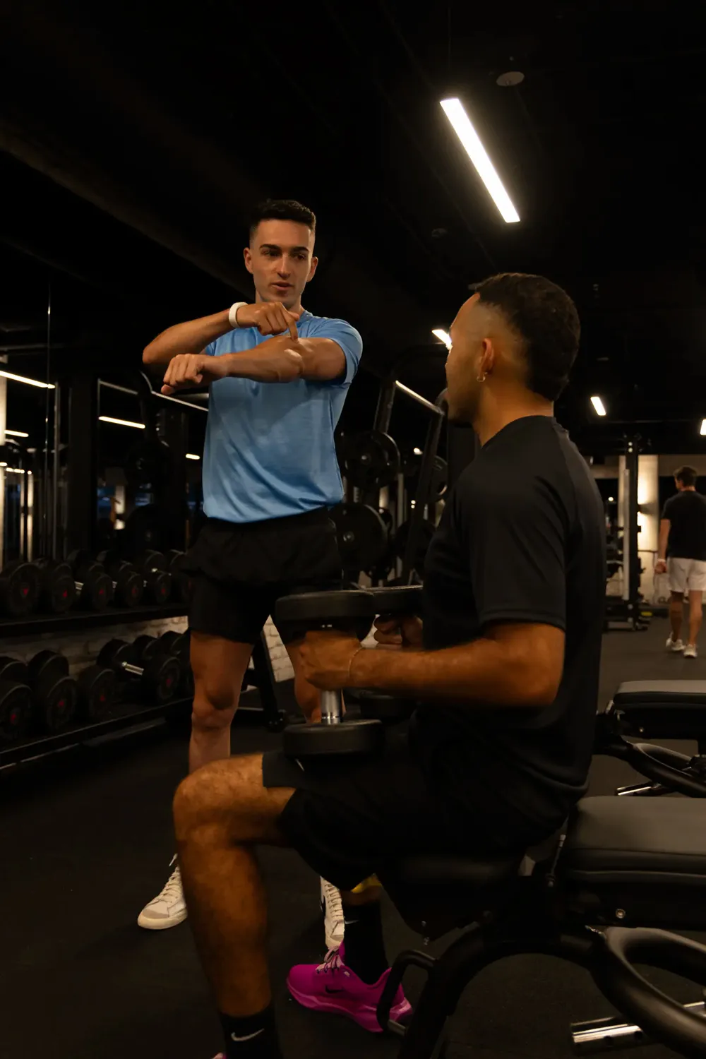 Trainer demonstrating dumbbell technique to a client during a strength session
