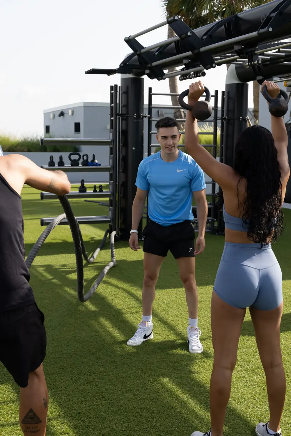 Trainer supervising a kettlebell workout at a rooftop terrace gym in Miami